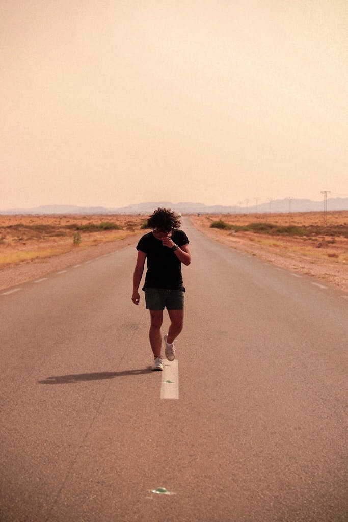 Man walking on isolated road in Gabes, Tunisia's semi-arid landscape. Captured in warm daylight.